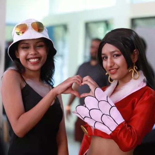 Two cosplayers pose to make a heart-shape